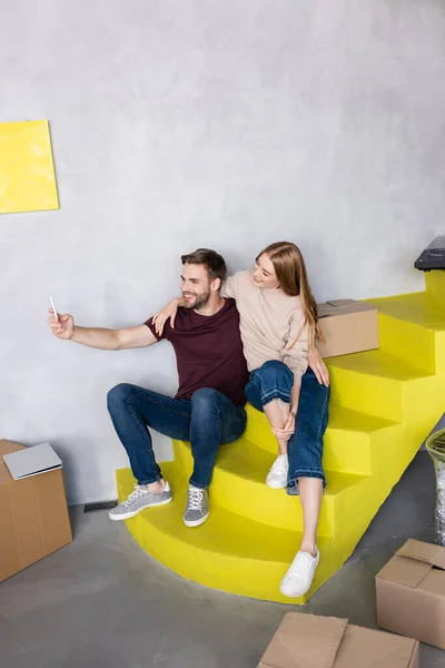 Nöjda Unga Par Sitter Gula Trappor Och Tar Selfie Nära — Stockfoto