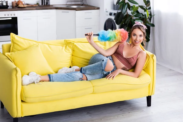 Young Housewife Holding Dust Brush While Lying Couch Home — Stock Photo, Image