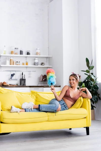 Young Housewife Holding Dust Brush While Lying Sofa Home — Stock Photo, Image