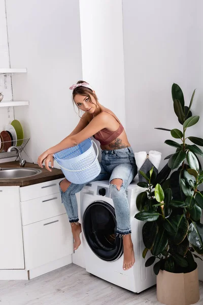 Young Woman Holding Laundry Basket While Sitting Washing Machine Kitchen — Stock Photo, Image