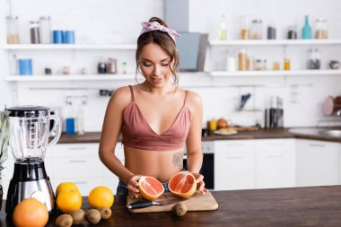 Ev hanımının meyve ve blender yanında greyfurt tutması seçici bir odak noktası 