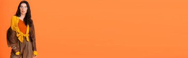 Sonbahar kıyafetleri ve turuncu üzerine izole edilmiş deri ceketli kadının panoramik oryantasyonu