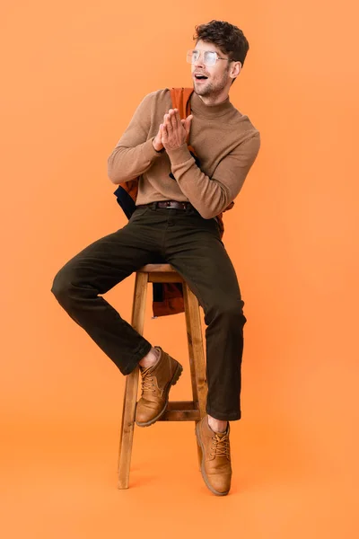 穿着秋装的时髦男人 戴着眼镜 双手叉腰坐在橙色的木制凳子上 — 图库照片