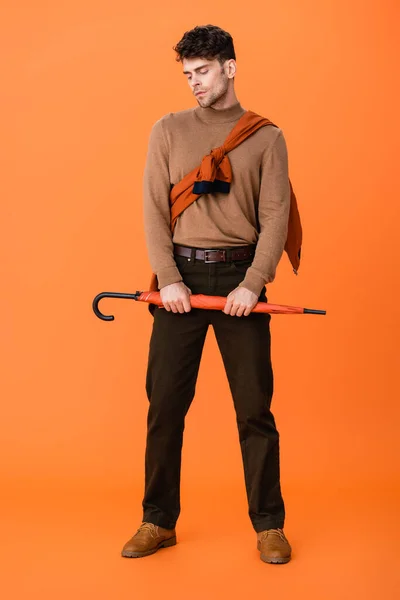 オレンジ色の傘を持っている秋の衣装のスタイリッシュな男の完全な長さ — ストック写真