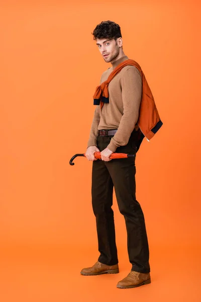 オレンジ色の傘を持っている秋の衣装の流行の男の完全な長さ — ストック写真