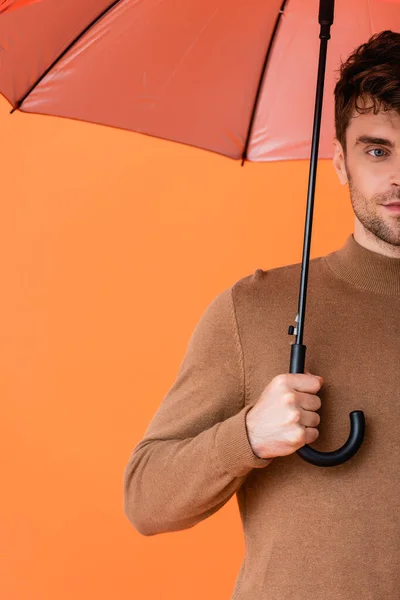 オレンジ色の傘を持っている秋の衣装のスタイリッシュな男のクロップドビュー — ストック写真
