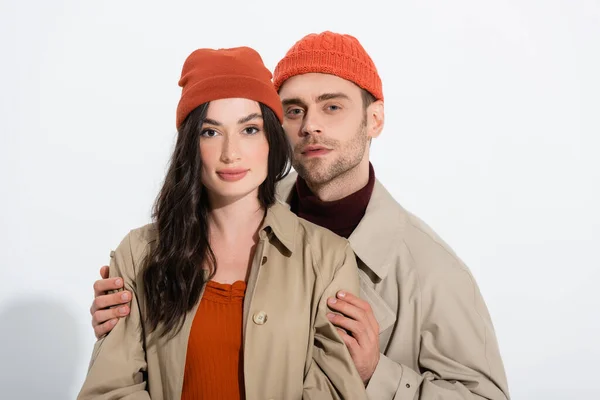 man in beanie hat touching stylish young woman on white