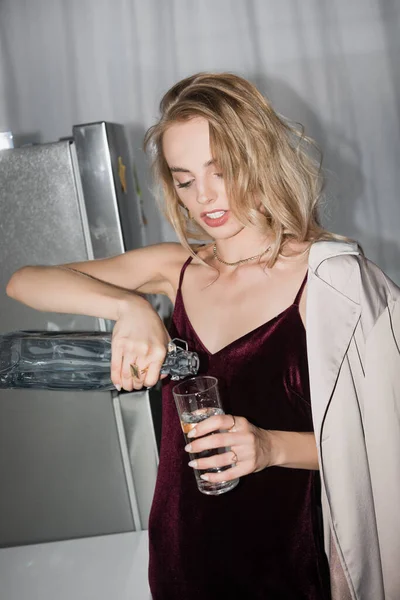 Blonde Woman Velour Dress Trench Coat Pouring Water Glass Kitchen — Stock Photo, Image