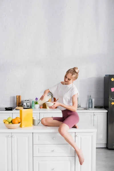 Mulher Descalça Shorts Derramando Leite Tigela Enquanto Sentado Mesa Cozinha — Fotografia de Stock
