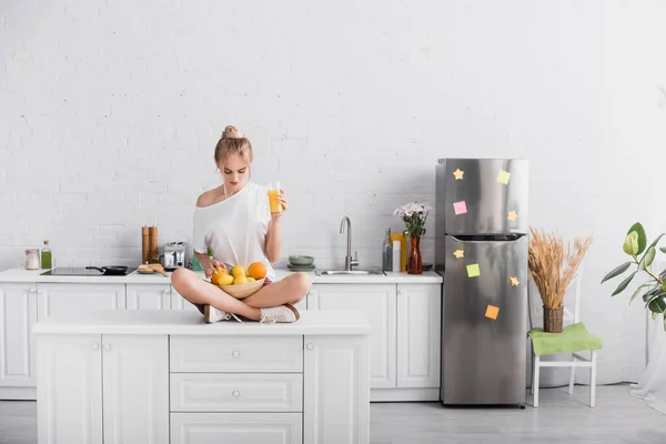 Ung Blond Kvinna Håller Apelsinjuice Medan Sitter Köksbordet Med Skål — Stockfoto