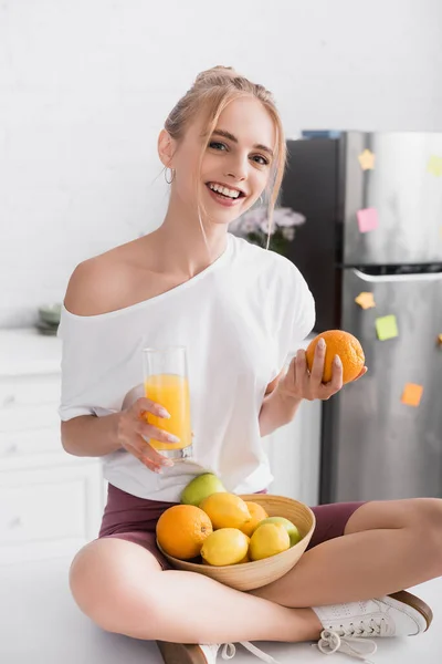Молода Блондинка Сидить Кухонному Столі Апельсиновим Соком Свіжими Фруктами — стокове фото