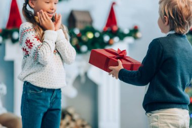 Çocuk, hayrete düşmüş ablaya Noel hediyesini sunuyor.