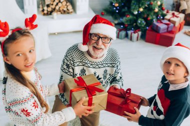 Mutlu büyükbaba Noel 'de torunlarından hediye kutuları alıyor.