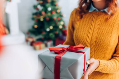 Elinde Noel hediyesi kutusu olan seçici odaklı kadın manzarası.