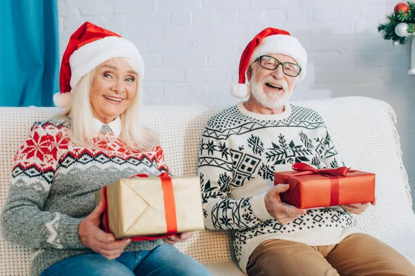 Happy Senior Couple Santa Hats Looking Camera While Sitting Sofa — Stock Photo, Image