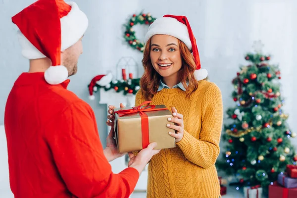 Selective Focus Excited Woman Santa Hat Taking Christmas Gift Husband — Stock Photo, Image