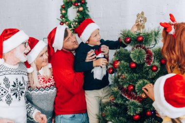 Baba oğluyla el ele tutuşup Noel ağacını aile ile süsledi.