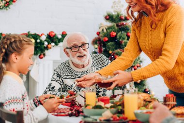 Selective focus of happy grandfather sitting at festive table with family clipart
