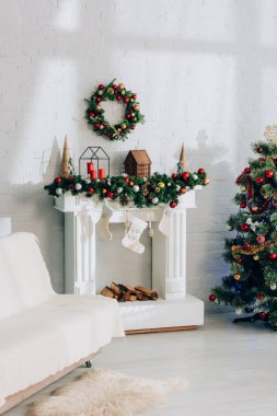 Şöminenin yanında battaniyeli kanepe, Noel çorapları ve süslü çam ağaçları.