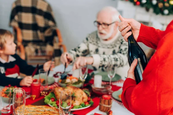 Seçici odak noktası aile ve şenlik masasının yanında şampanya şişesi açmak. 