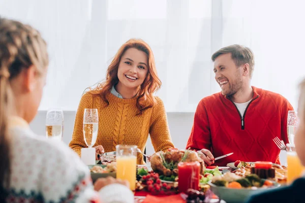 男人和女人坐在节日桌旁笑的选择性焦点 — 图库照片