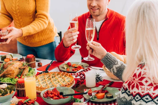テーブルで家族の近くに座って シャンパンと女性と男性の眼鏡を保持の作物のビュー — ストック写真