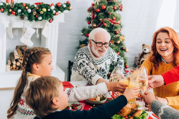 幸せな家族の乾杯 暖炉とクリスマスの松の近くのお祝いのテーブルに座って — ストック写真