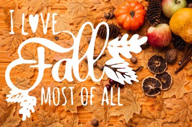 top view of autumnal decoration and food on golden leaves near i love fall most of all lettering on wooden background clipart
