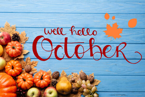 top view of autumnal harvest and leaves near well hello october lettering on blue wooden background