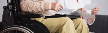 cropped view of disabled man looking at photos with social worker, banner clipart