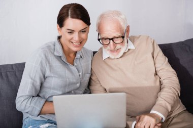 Güler yüzlü kadın konsantre babası evde dizüstü bilgisayar kullanıyor.