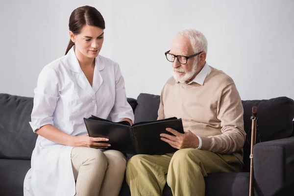 Morena Trabajador Social Anciano Hombre Mirando Álbum Fotos Casa — Foto de Stock