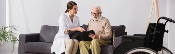 Enfermera Geriátrica Anciano Mirando Fotos Mientras Está Sentado Sofá Pancarta —  Fotos de Stock