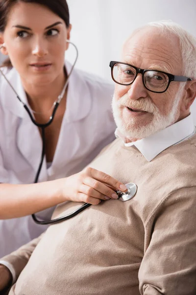 Medical Assistant Examining Aged Man Stethoscope Blurred Background — Stock Photo, Image