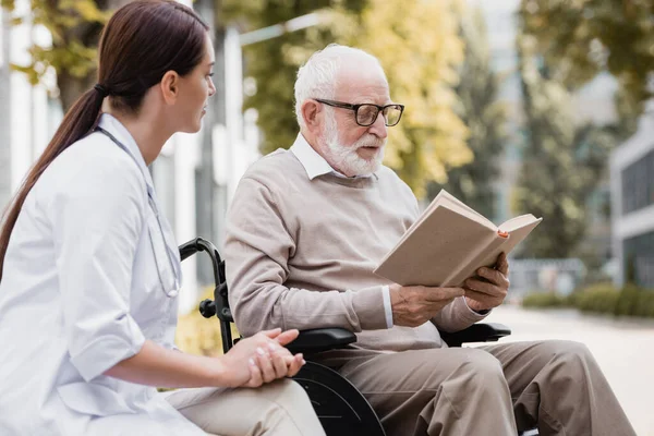 Disabled Man Eyeglasses Reading Book Social Worker Outdoors — Stock Photo, Image