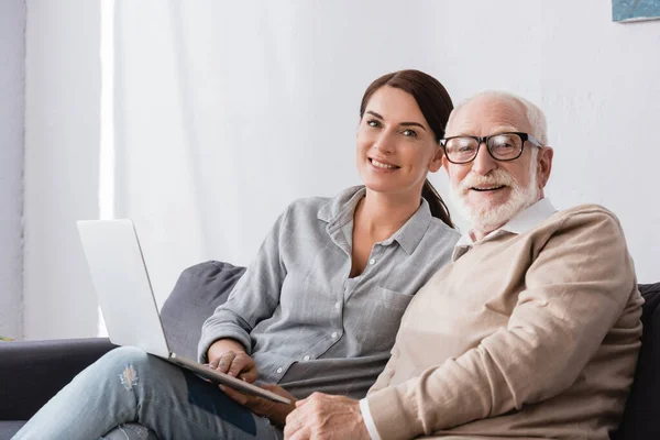 Smiling Brunette Woman Looking Camera While Sitting Aged Father Using — Stock Photo, Image