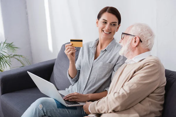 Smiling Woman Holding Credit Card Laptop Aged Father While Sitting — Stock Photo, Image