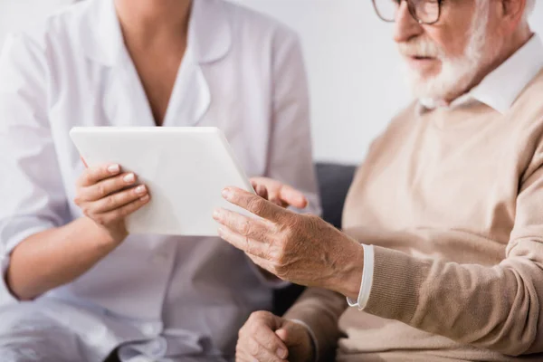 Corte Assistente Social Mostrando Tablet Digital Para Homem Idoso Casa — Fotografia de Stock