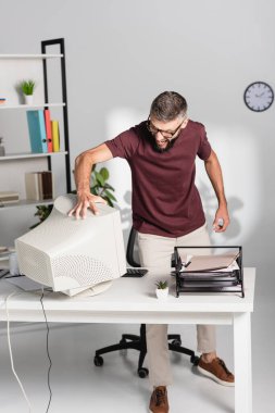 Ofis masasının yakınındaki bilgisayar monitörüne dokunurken saldırgan işadamı çığlık atıyor. 
