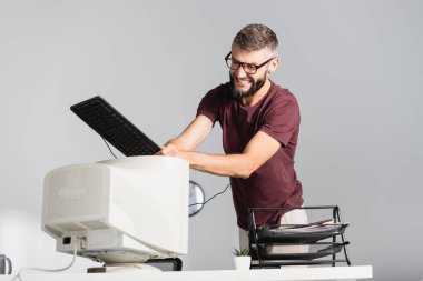 Ofisteki bulanık ön planda klavyeyle dövülen bilgisayar monitörüyle çılgın iş adamı