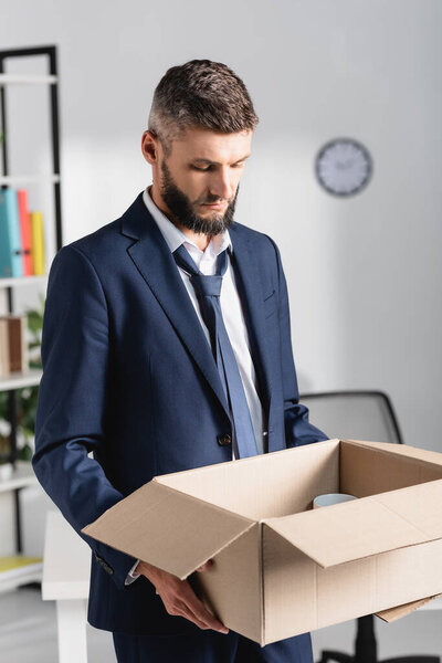 Sad businessman holding carton box in office 