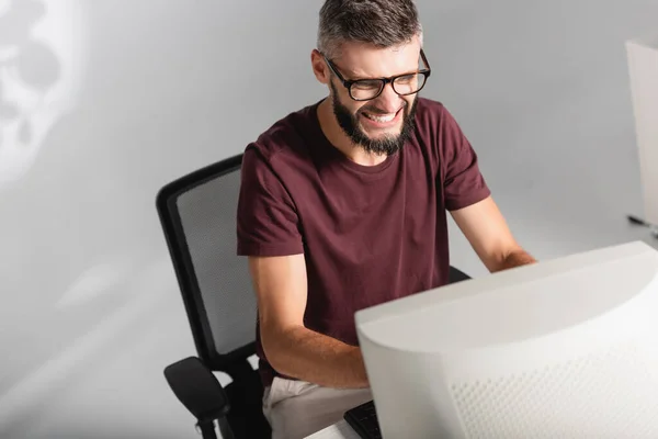 Aggressive businessman sitting near computer on blurred foreground in office