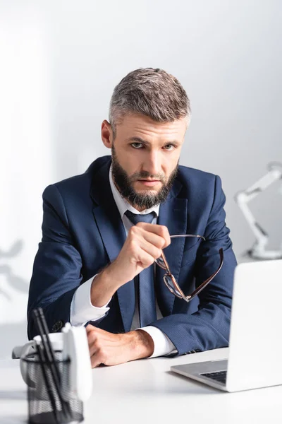 Bearded Businessman Holding Eyeglasses While Looking Camera Laptop Table — Stock Photo, Image