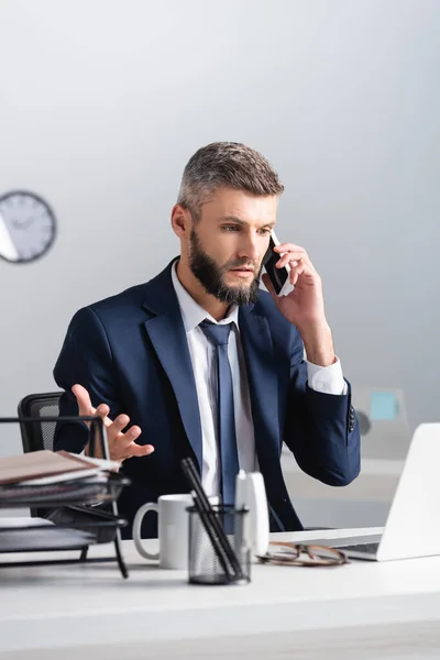 Adamı Bilgisayarın Yanında Akıllı Telefondan Konuşuyor Önplanda Bulanık Fincan Kırtasiye — Stok fotoğraf