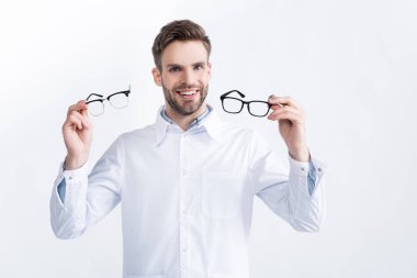 Front view of smiling ophthalmologist showing pair of eyeglasses, while looking at camera isolated on white clipart
