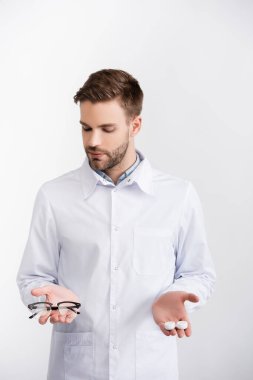 Avuç içlerindeki gözlük ve lensleri beyaza izole eden göz doktorunun ön görüntüsü.