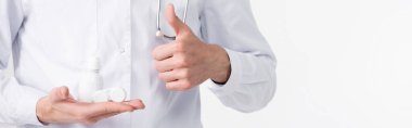 Doktorun beyaz pankarta izole edilmiş lensleri ve plastik şişeleri, baş parmağı yukarıda.