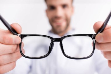 Siyah çerçeveli gözlük ve arka planda bulanık doktor.
