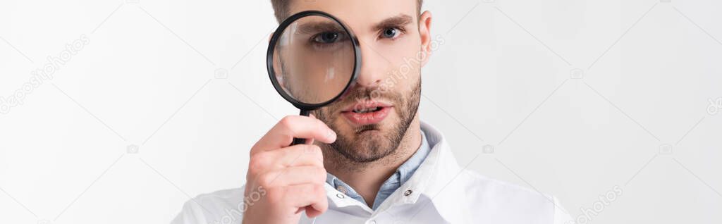 Portrait of bearded ophthalmologist looking through loupe isolated on white, banner