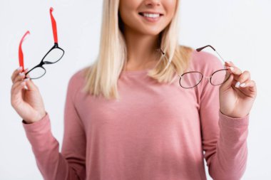 Cropped view of smiling woman holding eyeglasses on blurred background isolated on grey clipart